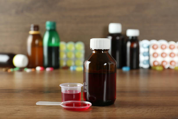 A clinical bottle of prescription cough syrup with codeine sitting on a sterile counter next to a precise dosing syringe